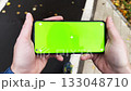 Handheld top view of person holding smartphone with green screen while walking 133048710