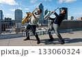 Two saxophonists play a duet on the roof of a high-rise building in the business district of a large city. 133060324