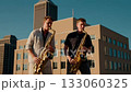 Two saxophonists play a duet on the roof of a high-rise building in the business district of a large city. 133060325