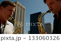Two saxophonists play a duet on the roof of a high-rise building in the business district of a large city. 133060326