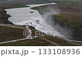 Gullfoss waterfall in Iceland plunges in two tiers into a canyon, with mist rising from the dynamic water. Visitors walk along pathways nearby. 133108936