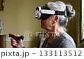 Senior woman with white hair using futuristic AR headset indoors. Concept of aging and technology in a modern setting. 133113512