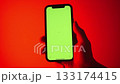 Male hand Holding Mobile Phone with Green Chroma Key Screen Mockup. Cellphone display close up. Business mockup empty blank space. VFX Motion Tracking Markers. Red Gradient Background 133174415
