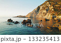 Rock formations scattered in shallow clear water by a cliff in Kefalonia island Greece at sunset 133235413