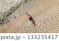 Beautiful woman relaxing on white pebble beach with sea waves washing ashore 133235417