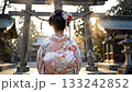 A woman in a kimono stands in front of the torii gate in the morning sun as she visits a shrine 133242852