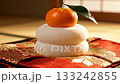 Kagami mochi and orange New Year's decorations on a cushion illuminated by sunlight 133242855