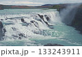 Huge waterfall view, Iceland nature landscape, serenity view of the waterfall, melting glacier water flow, tourist places and paths, green rocky terrain. 133243911
