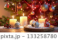 Glowing candles on fake snow with ornaments and festive christmas tree. 133258780