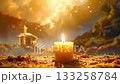 Candle burns brightly in front of distant temple in a golden landscape. 133258784