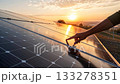 Checking the solar panels by hand against the background of sunset and sunlight 133278351