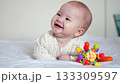 Baby lying on the bed and smiling happily in a bright cozy home environment 133309597