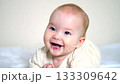 Baby lying on the bed and smiling sweetly in a close-up home portrait 133309642