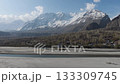 Aerial view of a serene village nestled in the mountains of Pakistan, showcasing traditional architecture and a majestic snow-capped peak in the background 133309745