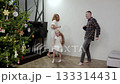 Happy family members moving rhythmically, dancing with festive energy near sparkling christmas tree, sharing seasonal celebration moment 133314431