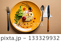 Creative and colorful arrangement of food on a yellow plate, with a fork, spoon, knife and napkin. 133329932