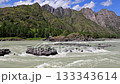 Wild Katun River rapid between mountains, milky glacial water rushing over boulder-strewn channel under vivid blue sky with scattered clouds, steep pine-clad, Altai 133343614