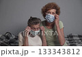 Elderly 90-year-old woman with her 60-year-old daughter sitting on a nursing home bed, hugging and smiling at the camera while gently removing a medical mask, showing warmth and family care 133343812