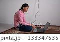Poor girl learning online at home on the floor with an old laptop 133347535