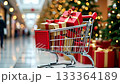 Shopping cart filled with beautifully wrapped gifts moves through a festive mall decorated for the holidays, showcasing vibrant colors and joyful atmosphere 133364189