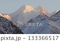 Majestic snow-capped mountains illuminated by golden sunlight, camera zooms in 133366517