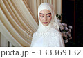 Chechen bride in hijab looks to the side standing by elegant wedding drapery 133369132