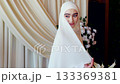 Chechen bride in hijab smiles gently during wedding ceremony in elegant interior 133369381