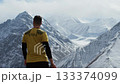 Adventurer gazes at majestic snow-capped mountains, camera pans slowly 133374099