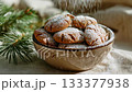 A rustic bowl of gingerbread cookie covered with powdered sugar and pine twig decoration on linen fabric in warm natural light 133377938