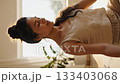 Vertical shot of smiling woman meditating with closed eyes. Peaceful morning atmosphere promotes wellness and mental health. Perfect for lifestyle and fitness projects. 133403068