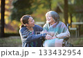秋の紅葉で介護する女性と車椅子の高齢者の見つめ合う介護士のような人 133432954