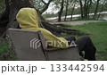 girl yellow hoodie sits motionless old vintage chair, hiding hands pockets admiring beauty local nature outside city, against backdrop large thick old willow tree beach river 133442594