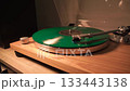 bright new green music vinyl record plays smoothly on the device. the needle slides over it. close-up.yellow lamp light 133443138