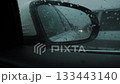 Close-up. Blind Spot Monitor Lights up on the side mirror of the car when overtaking, while driving on the road in the rain 133443140