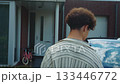 Young individual returns home from school, Teenager view from back as he walks home from walk past car, Youthful person walks to door beside their car in suburban neighborhood 133446772