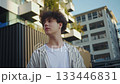 Teen boy observing, Teenage boy with curly hair studies architectural facades in city, Youthful male with striped shirt contemplates geometric buildings under warm sunlight in urban setting 133446831