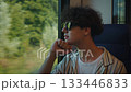Youthful traveler pondering, Teen looking through train glass, Adolescent watching countryside pass by through window, Youth immersed in reflective moment as lush landscape flows past window 133446833