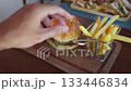 Juicy burger with a sesame seed bun, served alongside crispy french fries, ketchup, and mayonnaise, sits invitingly on a wooden board, promising a satisfying meal. poor nutrition 133446834