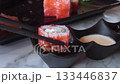 Two black ceramic dipping bowls filled with soy sauce and sesame dressing sit on marble table, with platter of sushi rolls softly blurred in background. Cuisine Japanese restaurants and sauces 133446837