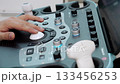 Close up of doctor operating ultrasound machine control panel. 133456253