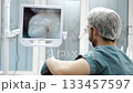 Dentist views intraoral camera image on monitor during dental exam. 133457597