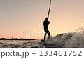 An Adventurous Watersports Experience: A Surfer Skillfully Riding Waves Against a Beautiful Sunset 133461752
