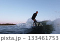 Fluid Motion and Skillful Balance: A Surfer Riding the Waves at Dusk, Capturing the Essence of Ocean 133461753