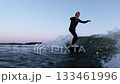 Dynamic Surfing Action: A Male Surfer Skillfully Riding the Waves Under a Beautiful Twilight Sky 133461996