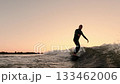 A Surfer Skillfully Rides a Wave at Sunset, Capturing the Thrill of Water Sports Against a Beautiful 133462006