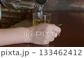 Pouring water from glass pitcher into glass on wooden table at home 133462412