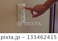Hand pressing light switch on beige wall, turning on electricity indoors 133462415