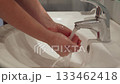 Person washing hands under running water in bathroom sink, hygiene routine 133462418