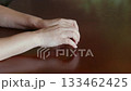 Woman hands clasped together on brown wooden table, expressing anxiety 133462425