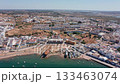 Aerial view drone shot of Ayamonte Aerial view fishing village and sandy beach with small skiffs moored, fishermen activity, shallow turquoise water and compact white coastal houses. 133463074